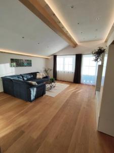 a living room with a black couch and wooden floors at Alex´s Ferienwohnung in Altaussee