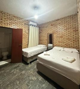 a bedroom with two beds and a brick wall at Hotel Olho D'água - Baturité in Baturité