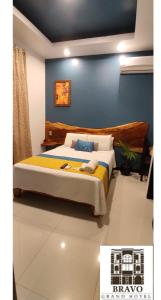 1 dormitorio con cama y pared azul en HOTEL BRAVO GRAND HOTEL, en Quevedo