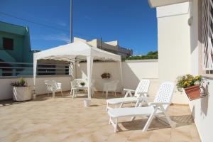 un patio con sillas blancas y una sombrilla en Il mare di Totino - Seaside guest house - Torre San Giovanni, en Torre San Giovanni