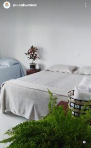 a bed with white sheets and a basket of towels at Pousada Venture Jalapao in São Félix do Tocantins