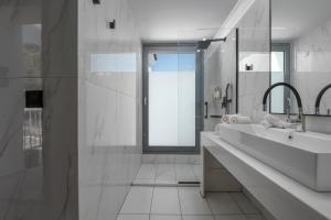 a white bathroom with a sink and a shower at Adrina Grand Hotel in Panormos Skopelos