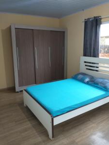 um quarto com uma cama com lençóis azuis e armários de madeira em Casa próxima ao shopping Lages e a festa do pinhão em Lages