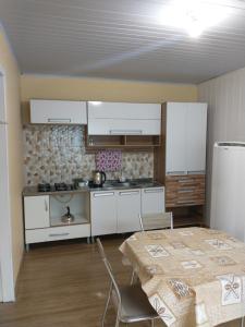 a kitchen with white cabinets and a table and chairs at Casa próxima ao shopping Lages e a festa do pinhão in Lages