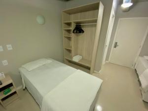 Un pequeño dormitorio con una cama blanca y un armario en Coral Express , próximo ao Embarcadeiro, en Porto Alegre