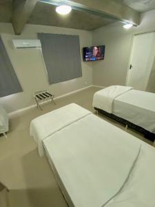 a room with two beds and a tv in it at Coral Express , próximo ao Embarcadeiro in Porto Alegre