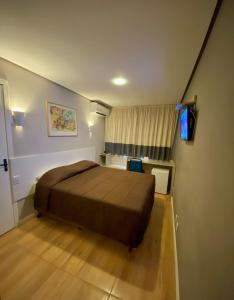 um quarto com uma cama e uma televisão em Coral Express , próximo ao Embarcadeiro em Porto Alegre