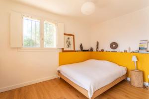 um quarto com uma cama branca e uma parede amarela em Appartement Terrasse plein sud en pleine nature em Aubagne