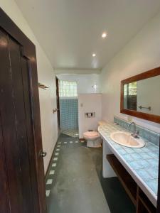 a bathroom with a sink and a toilet and a mirror at Villas Punta India in Playa Ostional