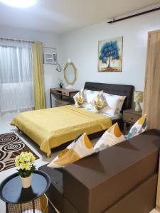 a bedroom with two beds and a table in it at DELUXE ROOM Queen Bed & Sofa Bed with Balcony and Swimming Pool at PPS in Puerto Princesa City