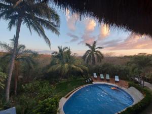 a swimming pool with chairs and palm trees at Villas Punta India in Playa Ostional