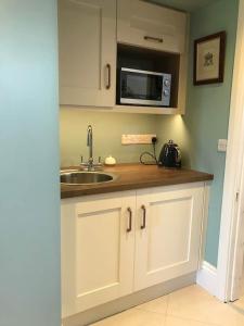 eine Küche mit einer Spüle und einer Mikrowelle in der Unterkunft Ballea Castle in Cork
