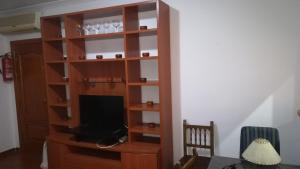 a wooden book shelf with a television in a room at Hostal Colon Antequera in Antequera