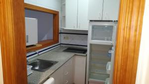 una pequeña cocina con fregadero y nevera vacía en Hostal Colon Antequera, en Antequera