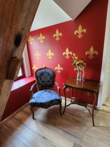 Cette chambre dispose d'une chaise et d'une table avec un vase de fleurs. dans l'établissement La Perchonniere, à Mamers