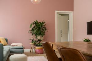 sala de estar con paredes rosas, mesa y sillas en Vakantiewoning 't Hovenshuis en Kinrooi