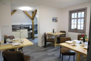 a restaurant with wooden tables and chairs and a kitchen at Conny's Träumerei in Bad Lobenstein