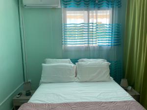 een bed met witte kussens in een slaapkamer met een raam bij Appartement Hibiscus in Basse-Terre