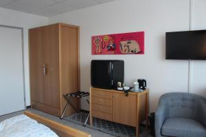 ein Wohnzimmer mit einem TV und einem Stuhl in der Unterkunft Gästehaus St. Martin in Ulmen