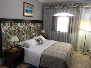 a bedroom with a bed and two lamps and a window at hotel fazenda encanto in Guararema