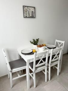 a white dining room table and chairs with food on it at Jaukūs apartamentai Šilutėje in Šilutė