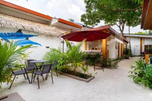 une terrasse avec une table, des chaises et un parasol dans l'établissement Tropico villa, à Ukulhas