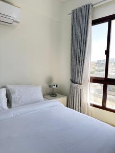 een slaapkamer met een wit bed en een raam bij City Gem BAQ in Muscat