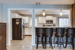 a kitchen with white cabinets and black bar stools at Shirley Vacation Rental with Hot Tub, 7 Mi to Beach! in Shirley