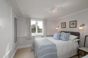 a bedroom with a bed with blue pillows and a window at Charming Barn Retreat Near Pewsey & Woodborough in Woodborough