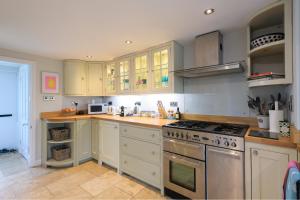 a kitchen with white cabinets and a stove top oven at Charming Barn Retreat Near Pewsey & Woodborough in Woodborough