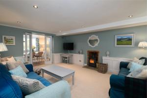 a living room with blue furniture and a fireplace at Charming Barn Retreat Near Pewsey & Woodborough in Woodborough