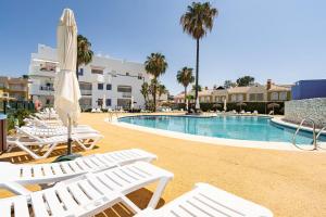 a swimming pool with white lounge chairs and an umbrella at Casa Islantilla Real in Huelva