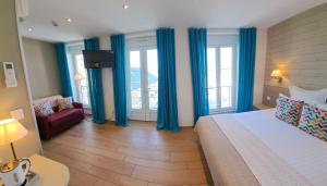 a bedroom with blue curtains and a bed and a couch at La Maison Du 6 in Arromanches-les-Bains