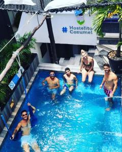 un groupe de personnes assises dans une piscine dans l'établissement Hostelito Hotel, à Cozumel