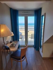 a hotel room with a desk and a view of the ocean at La Maison Du 6 in Arromanches-les-Bains