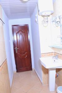 a bathroom with a brown door and a sink at Very secure apartment Bole Addis Enyi Real Estate in Addis Ababa