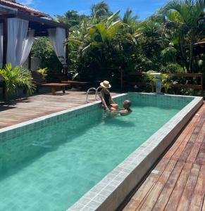 Chalés Mãe Natureza - Reserva do Matuto في فيرا كروز دو إيتاباريكا: جلوس شخصين في مسبح