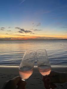 duas pessoas a segurar copos de vinho na praia em Chalés Mãe Natureza em Vera Cruz de Itaparica