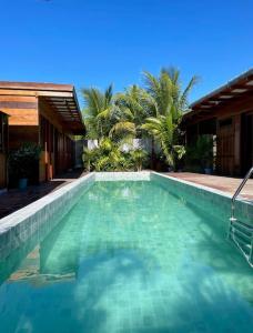 een zwembad naast een huis met palmbomen bij Chalés Mãe Natureza in Vera Cruz de Itaparica