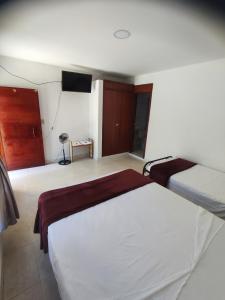 a bedroom with two beds and a flat screen tv at Hospedaje villa luz in Pitalito