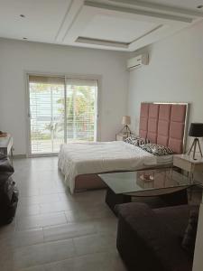 a bedroom with a bed and a couch and a table at Amazing villa next to the beach in Nabeul