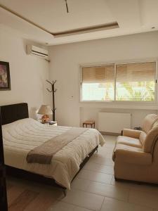 a bedroom with a large bed and a couch at Amazing villa next to the beach in Nabeul