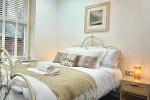 a white bedroom with a bed with pillows at Central Buxton apt in Spring Gardens in Buxton