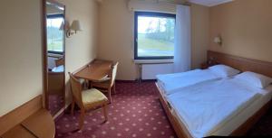 Hotel de la Station في Scheidgen: غرفه فندقيه بسرير ومكتب ونافذه