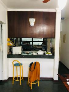 a kitchen with two yellow stools and a counter at Apartamento Aconchegante - Boraceia (Bertioga) in Bertioga