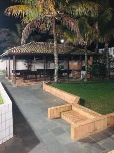 a park with a bench and a pavilion with palm trees at Apartamento Aconchegante - Boraceia (Bertioga) in Bertioga