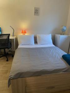 a bedroom with a bed with a desk and a lamp at chambre double std in Longjumeau