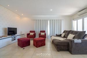 ein Wohnzimmer mit einem Sofa und zwei roten Hockern in der Unterkunft Casa de luxo com vista para o mar, Itapema CDP025 in Itapema