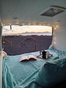 uma cama numa tenda com uma mesa e um livro em Camperita Van Life em Puerto del Carmen