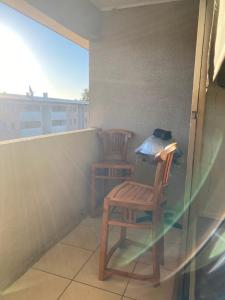 two wooden chairs sitting on a balcony with a window at Departamento Centro Curicó in Curicó